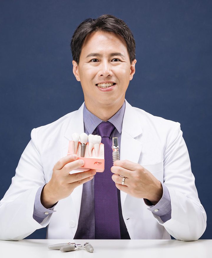 Dr. Daniel Kao holding a dental implant model